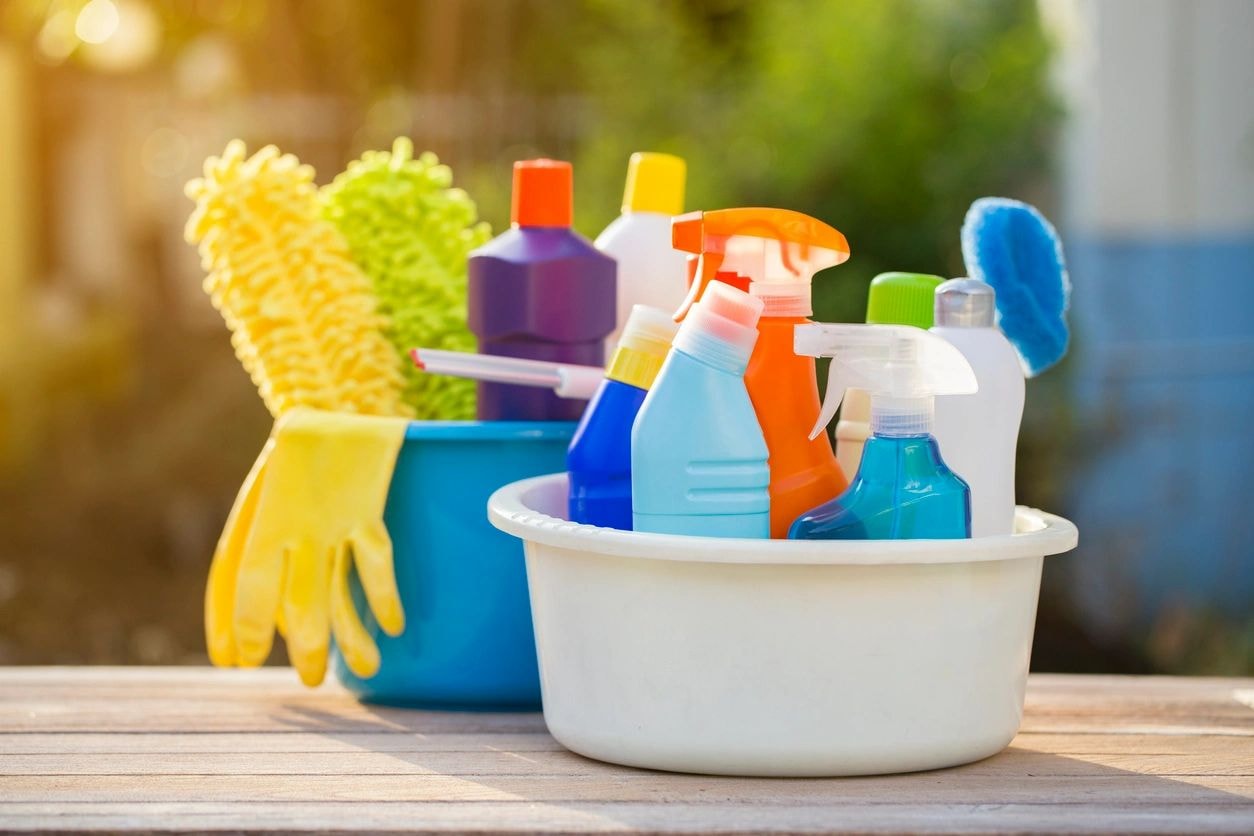 Cleaning supplies and tools in buckets on a wooden surface